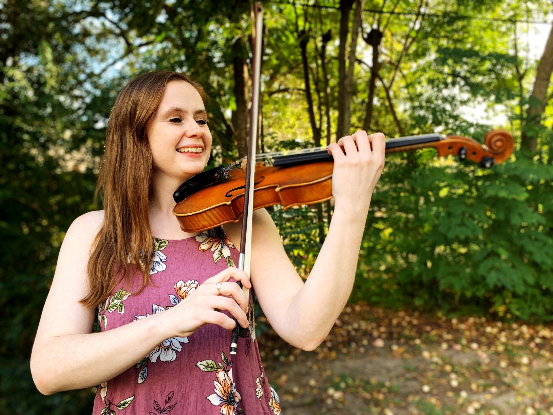 Meghan Faw smiling while playing violin outdoors